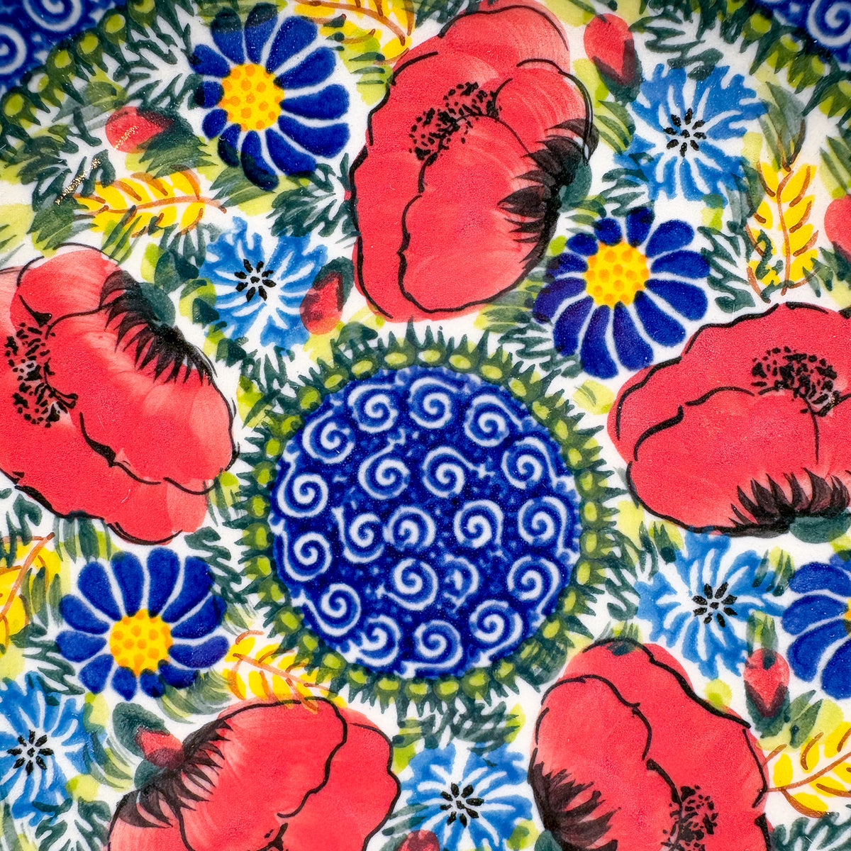 UNIKAT Garden Poppy plate, close-up top-down view of red poppies and blue spiral center