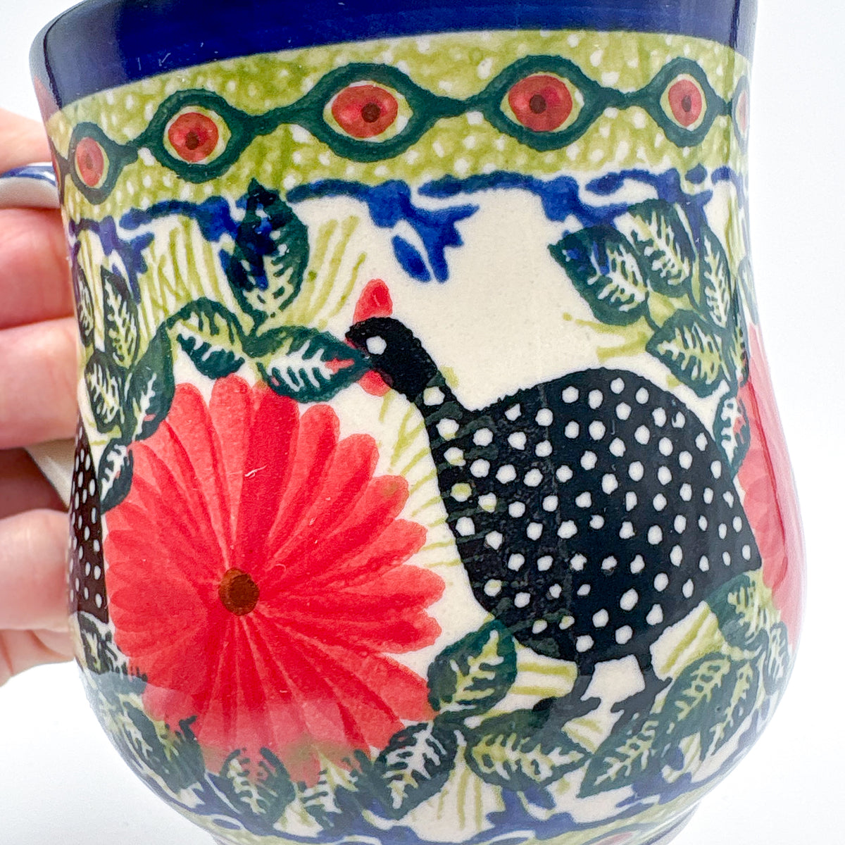 Close-up of guinea fowl and red flower on Fowls in Florals bubble mug, held in hand