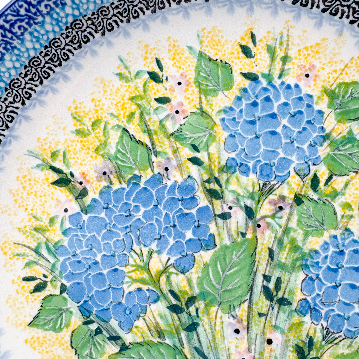 UNIKAT Blue Hydrangea plate, close-up top-down view of hydrangea blooms on yellow dotted field