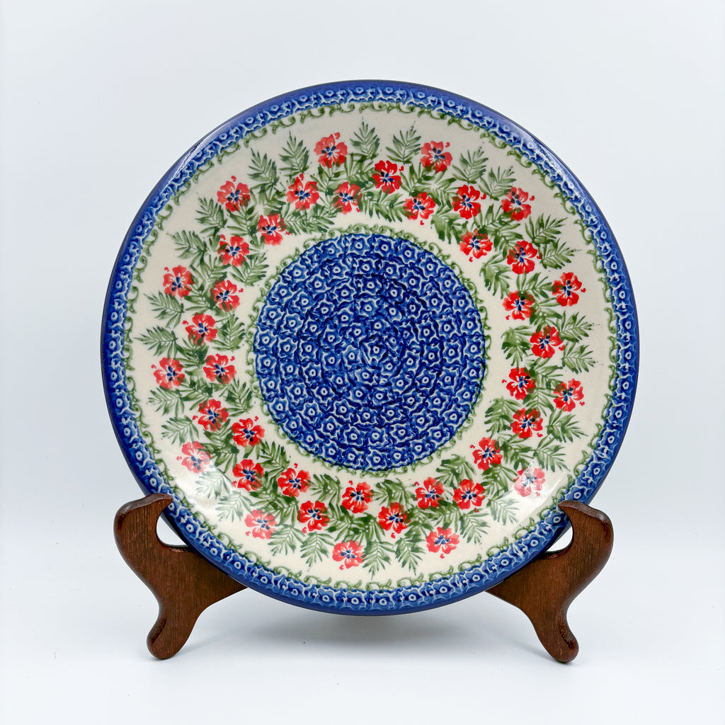 Midsummer Bloom plate, front view displayed on wooden stand showing red flower ring around blue center