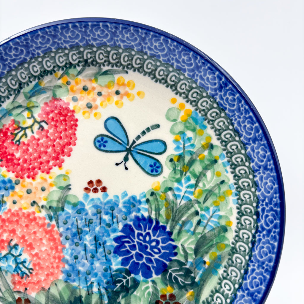 UNIKAT Garden Delight plate, close-up top-down view of dragonfly and pom-pom flowers