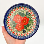 UNIKAT Happiness plate held in hand, front view showing red poppy cluster and Greek key border