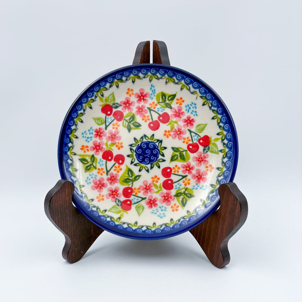 UNIKAT Cherry Blossom plate, front view displayed on wooden stand showing cherry and pink blossom ring