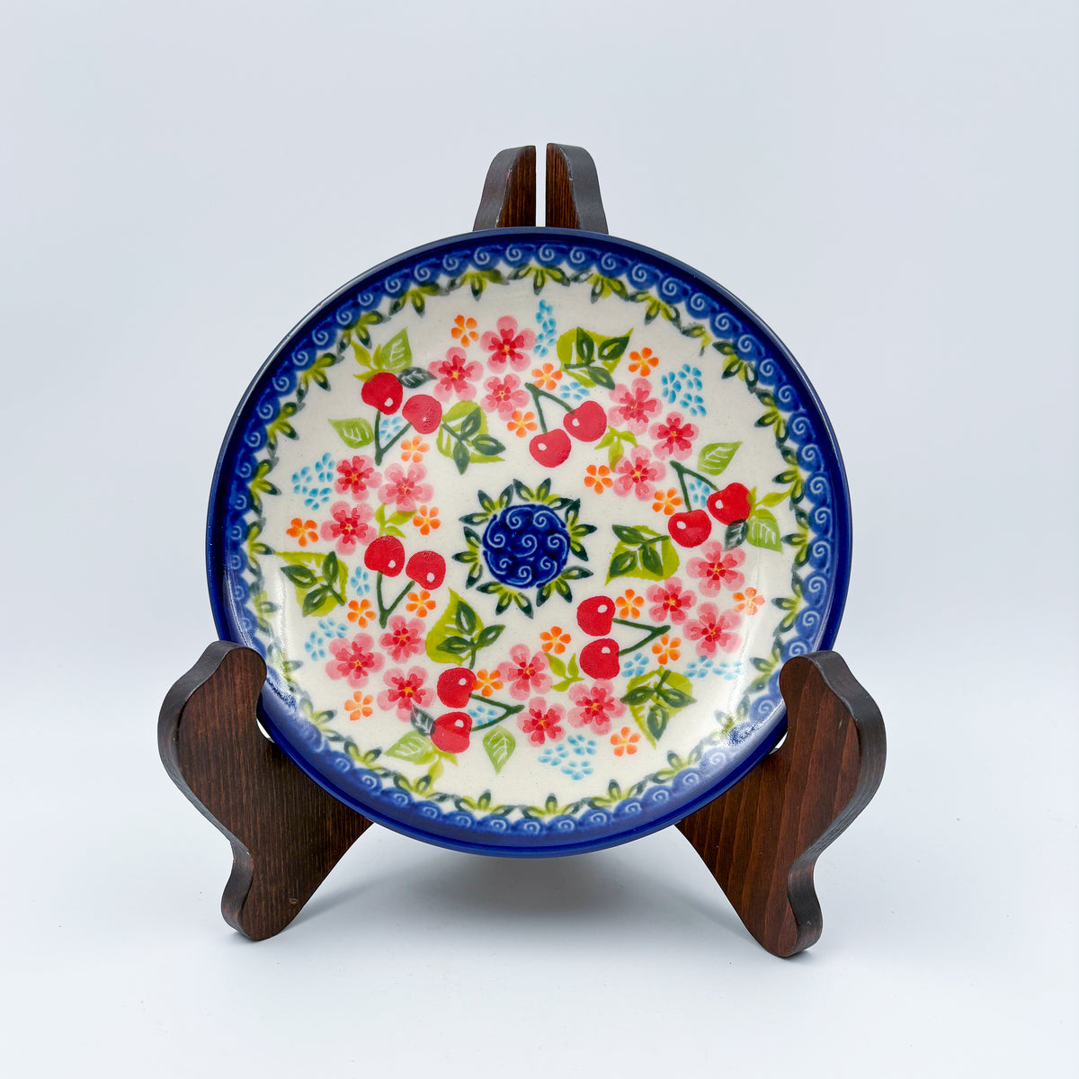 UNIKAT Cherry Blossom plate, front view displayed on wooden stand showing cherry and pink blossom ring