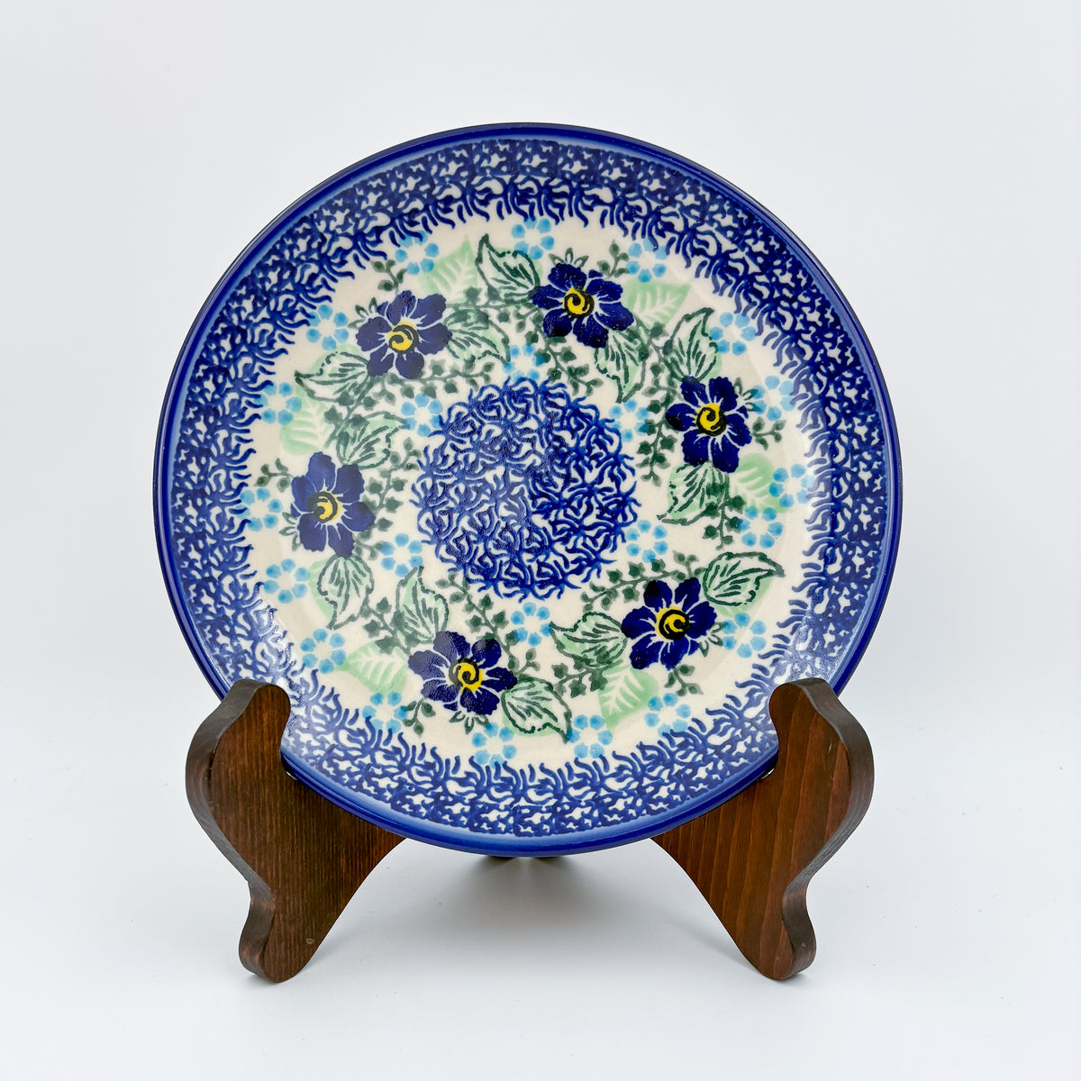 UNIKAT Blue Floral Day plate, front view displayed on wooden stand showing blue flower ring and mosaic center