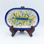 UNIKAT Wildflower Meadow oval platter, front view displayed on wooden stand showing wildflower spray
