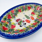 UNIKAT Berry Snowman oval Milano platter, angled top-down view of snowman, presents, and berry pine border