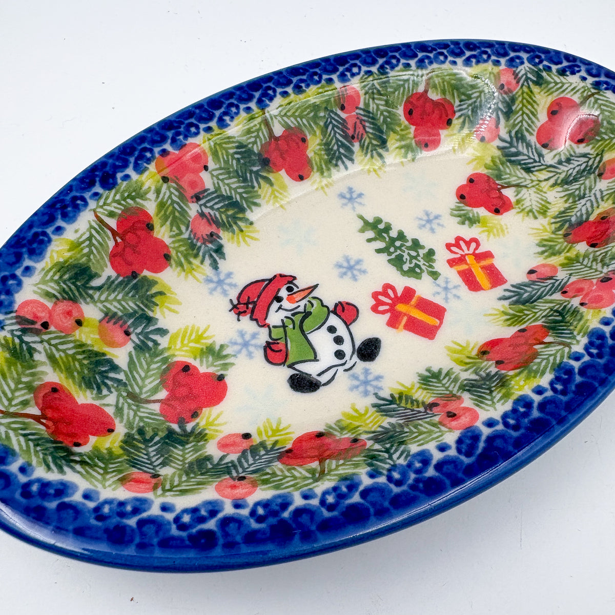UNIKAT Berry Snowman oval Milano platter, angled top-down view of snowman, presents, and berry pine border