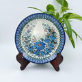 UNIKAT Blue Beauty plate, front view displayed on wooden stand showing blue daisy bouquet