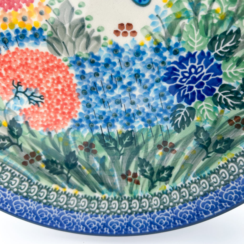 UNIKAT Garden Delight plate, close-up view of coral pom-pom flowers, hydrangea, and blue dahlia