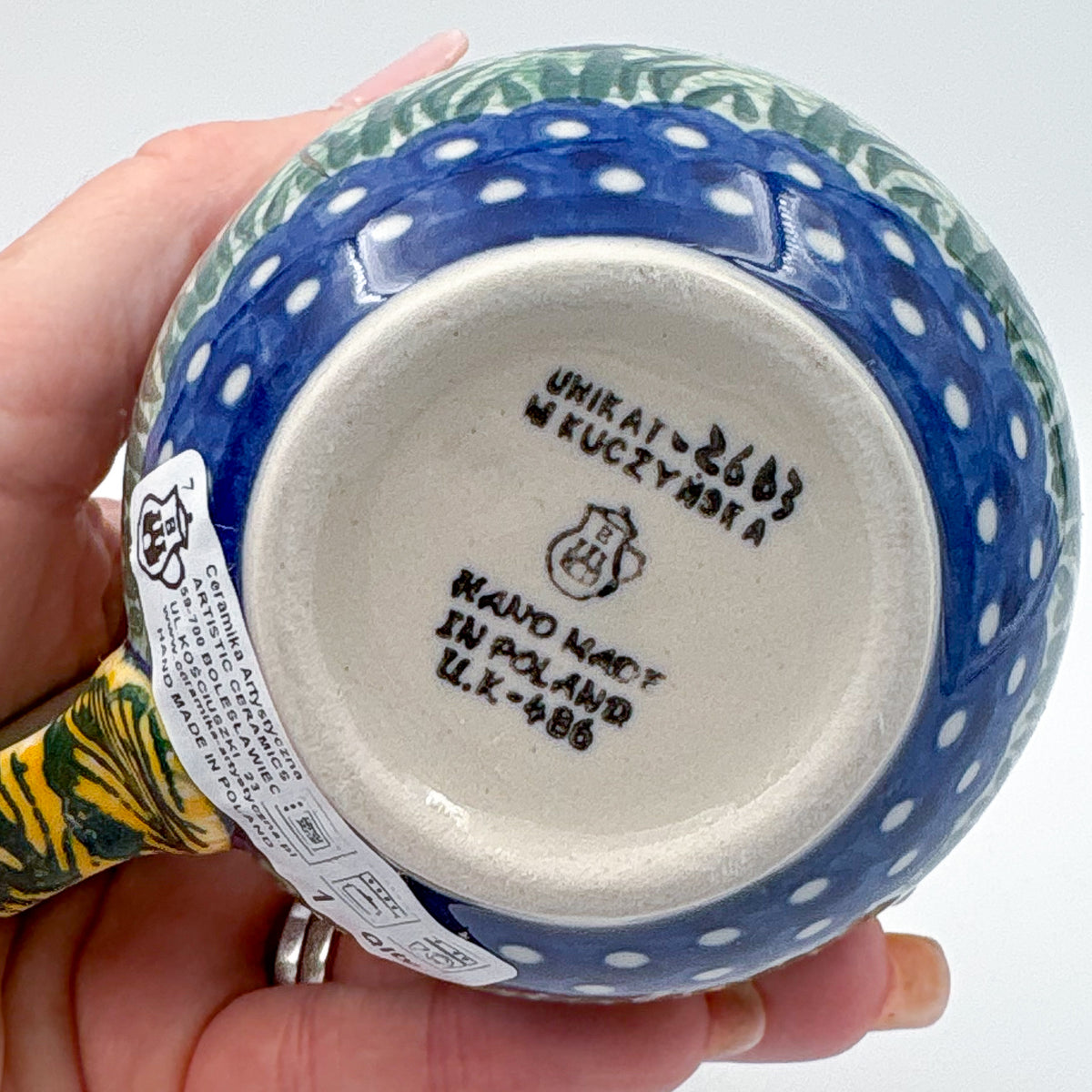 Bottom of Rooster Parade bubble mug showing Unikat stamp and artist signature, held in hand