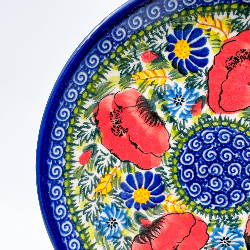 UNIKAT Garden Poppy plate, close-up rim view of red poppies, blue daisies, and spiral center