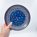 UNIKAT Cobalt Poppies dessert plate held in hand, front view showing blue poppy cluster and dotted border
