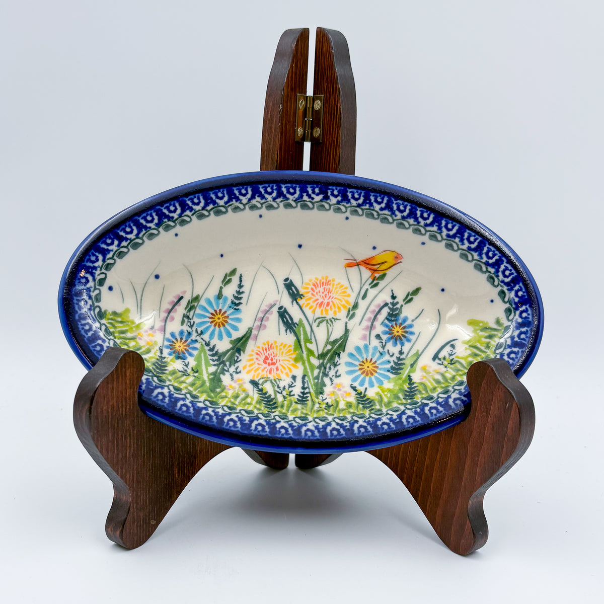 UNIKAT Songbird Garden oval Milano platter, front view on stand showing garden flowers and orange songbird