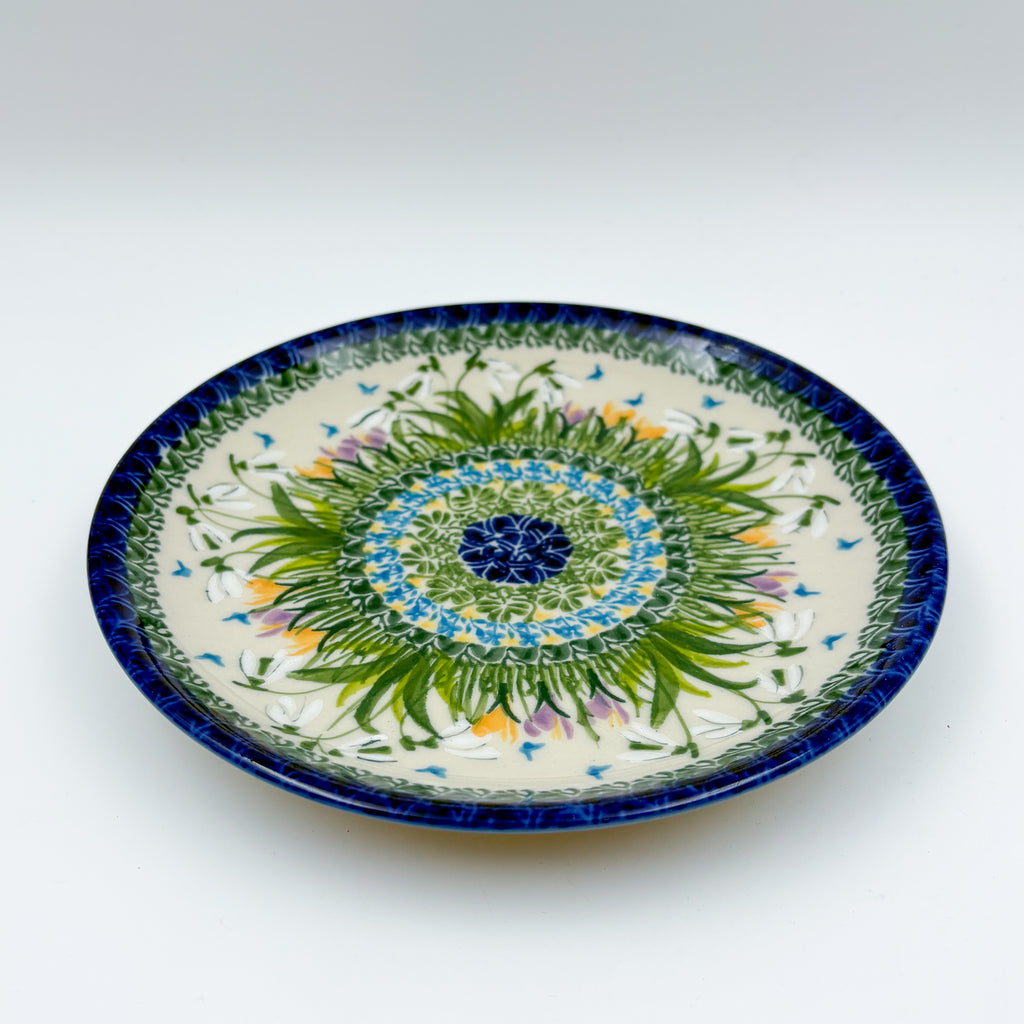 UNIKAT Snowdrop Garden plate, front view showing green grass burst and blue spiral rim