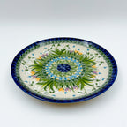 UNIKAT Snowdrop Garden plate, front view showing green grass burst and blue spiral rim