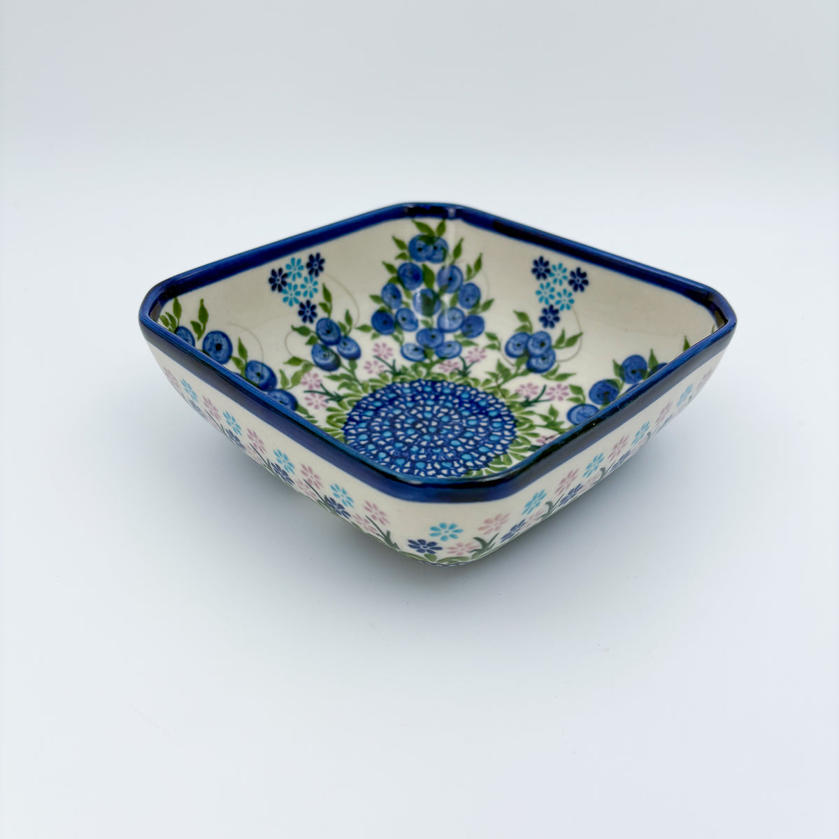 Blueberries square bowl on white background, angled front view showing depth