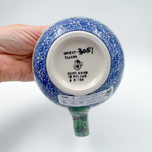 Bottom of Deep Winter latte mug showing Unikat stamp and artist signature M. Starzyk, held in hand