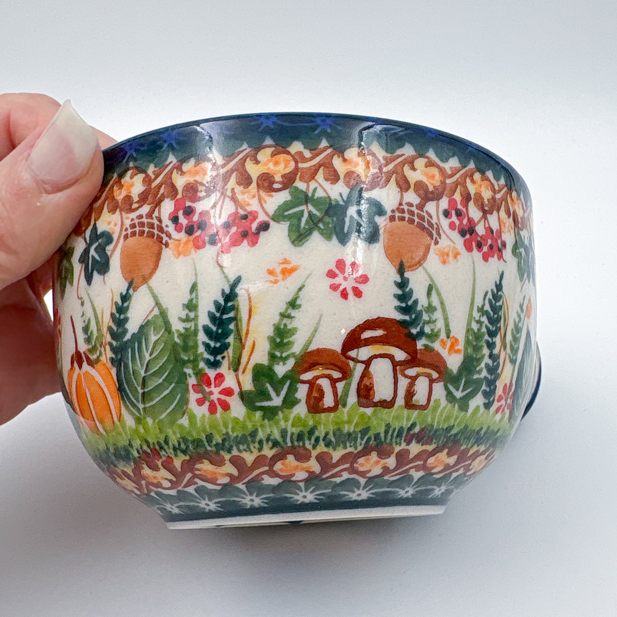 Close-up of mushrooms and acorns on Hedgehog and Acorns latte mug, held in hand