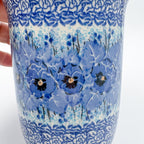 Close-up of blue pansy pattern on Deep Winter latte mug, held in hand
