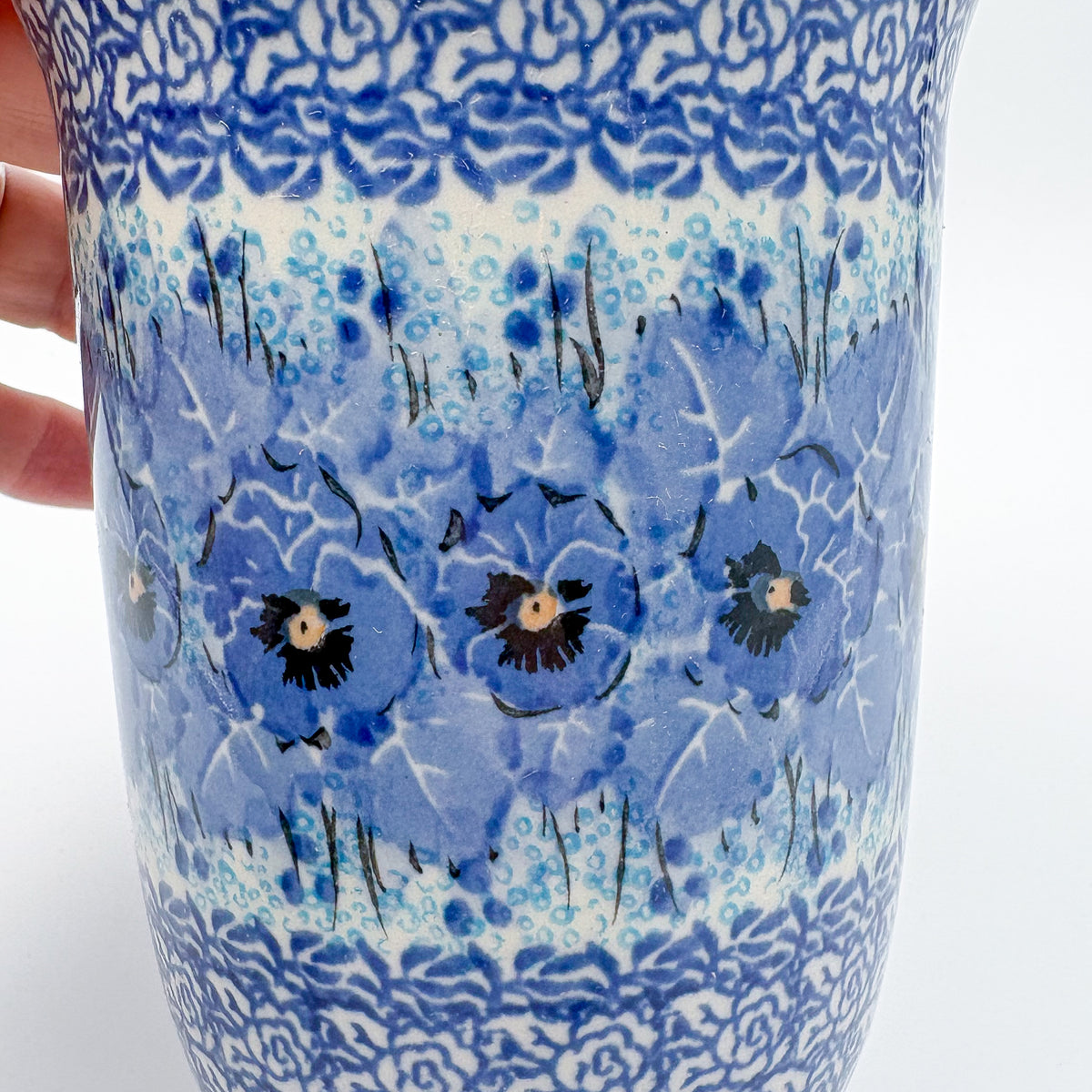 Close-up of blue pansy pattern on Deep Winter latte mug, held in hand