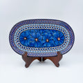 Cobalt Poppies oval platter, front view on stand showing row of blue poppy flowers and dotted mosaic border