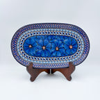 Cobalt Poppies oval platter, front view on stand showing row of blue poppy flowers and dotted mosaic border