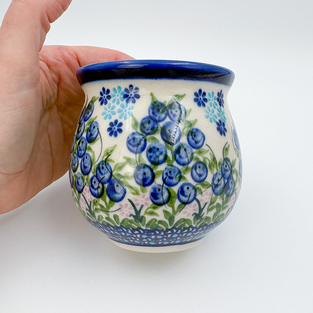 Blueberry bubble mug held in hand, front view showing blueberry sprig pattern