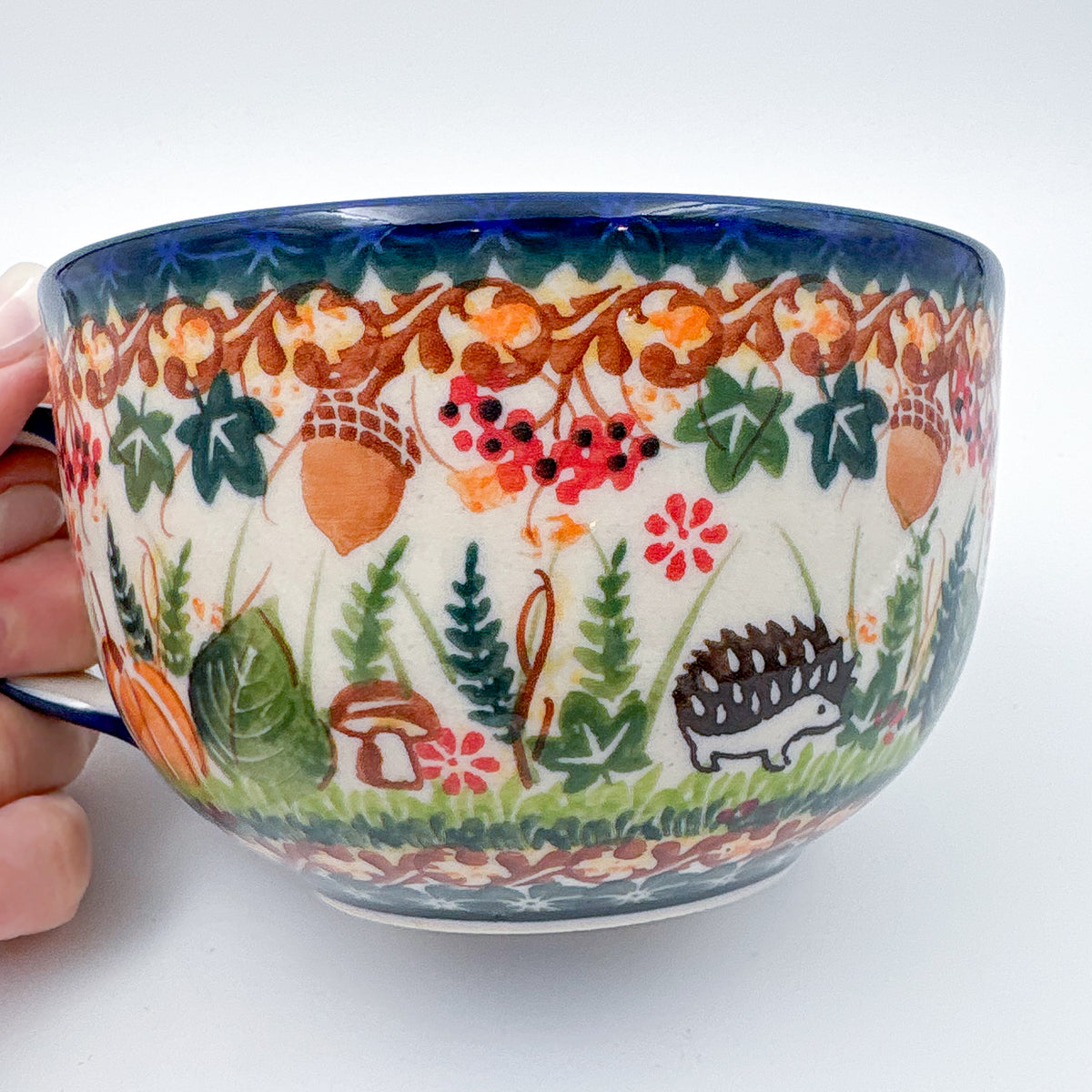 Close-up of hedgehog design on Hedgehog and Acorns latte mug, held in hand