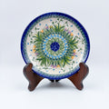 UNIKAT Snowdrop Garden plate, front view displayed on wooden stand showing green grass burst with snowdrops and crocuses