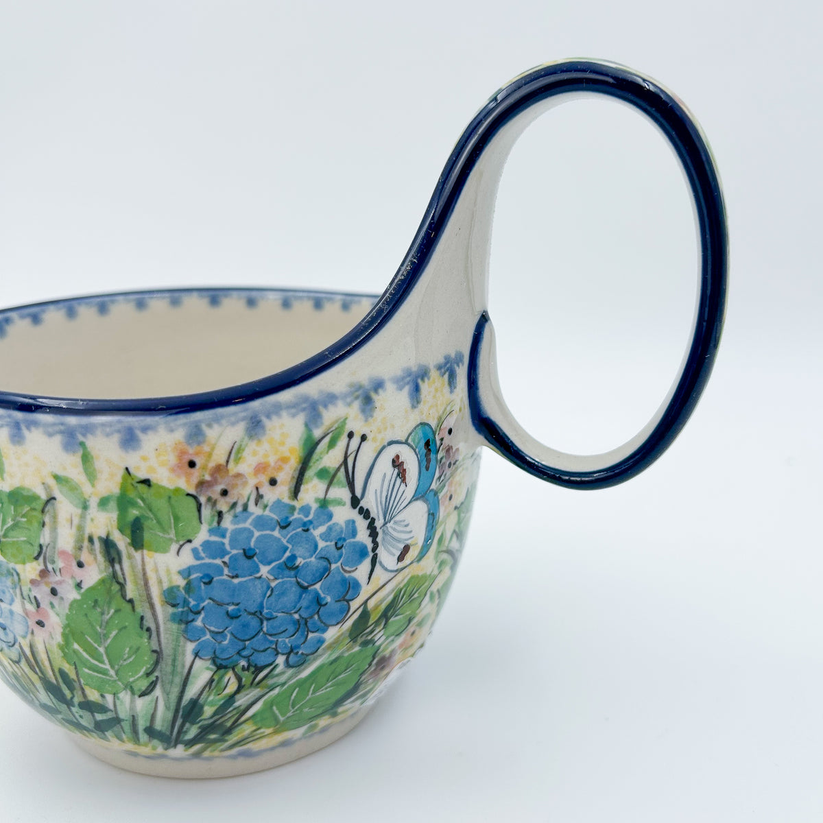 Polish pottery 16oz bowl with loop handle in the UNIKAT Blue Hydrangea pattern. This Polish Pottery bowl is made by talented artisans from Poland. 
6.26" x 4.49" x 5.51"
Ceramika Artystyczna Company