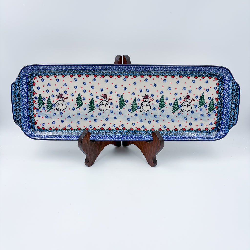 UNIKAT Snowman Stroll rectangular platter with handles, front view on stand showing snowmen and pine trees