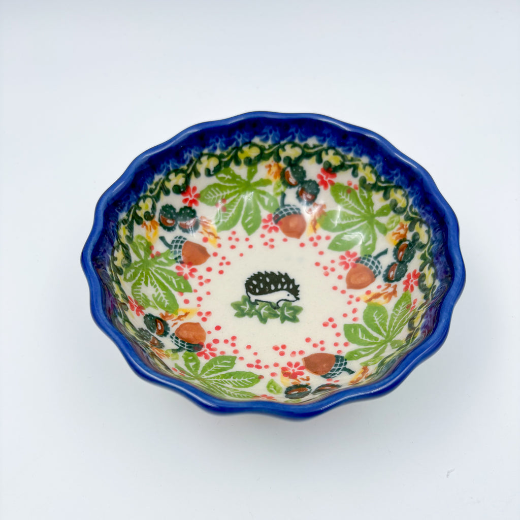 UNIKAT Hedgehog and Pumpkin scalloped bowl, top-down view showing hedgehog center with autumn leaf and acorn border