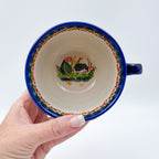 Top-down view into Hedgehog and Acorns latte mug showing hedgehog design, held in hand