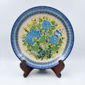 UNIKAT Blue Hydrangea plate, front view displayed on wooden stand showing blue hydrangea bouquet and butterfly