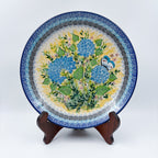 UNIKAT Blue Hydrangea plate, front view displayed on wooden stand showing blue hydrangea bouquet and butterfly