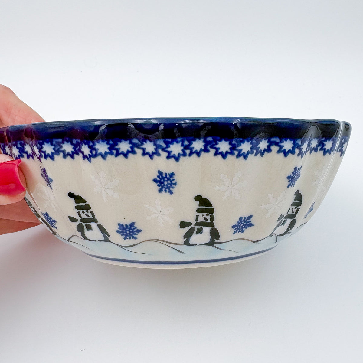 Snowman Penguins Design shell bowl, exterior side view held in hand showing snowman figures walking