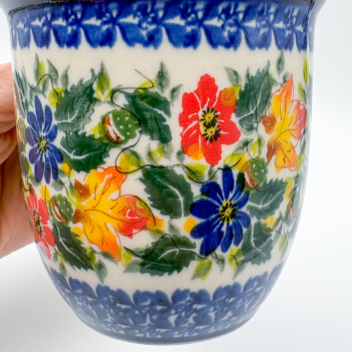 Close-up of autumn leaf and floral pattern on Fall Colors Viking mug, held in hand