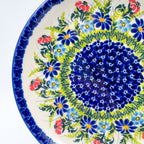 UNIKAT Meadow Breeze plate, close-up rim view showing blue wildflower ring on scalloped border