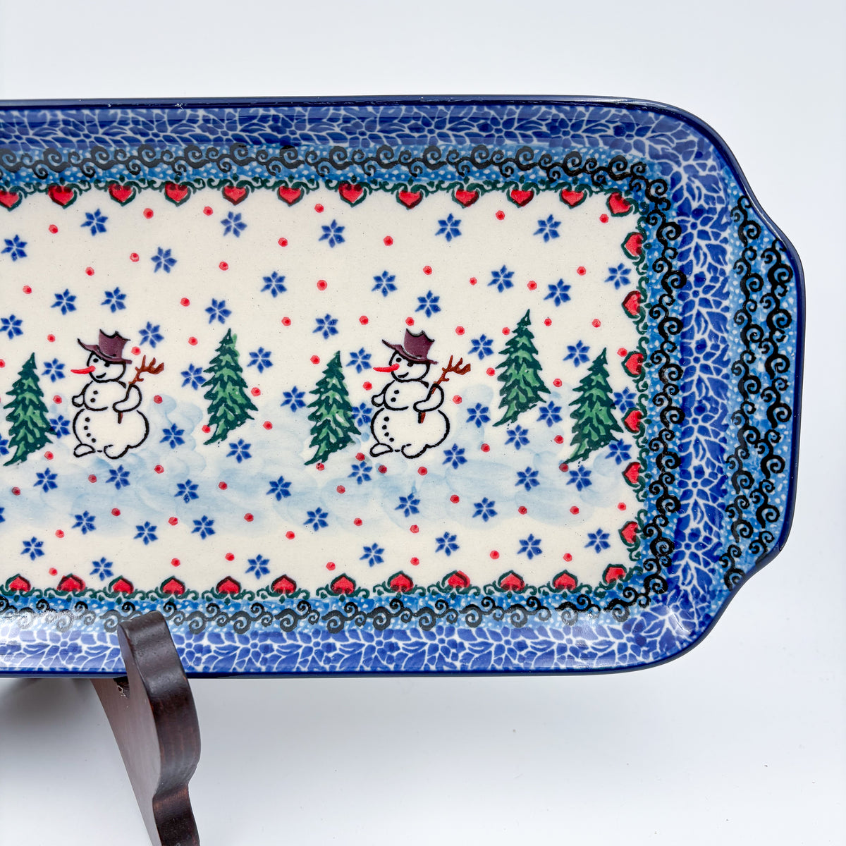 UNIKAT Snowman Stroll rectangular platter, close-up top-down view of snowmen with top hats and pine trees, snowflake field and heart border