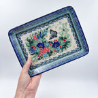 Mariposa rectangular platter held in hand, close-up corner view showing butterfly and floral bouquet