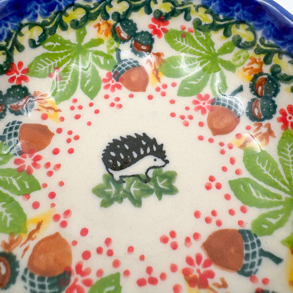 UNIKAT Hedgehog and Pumpkin scalloped bowl, close-up top view of hedgehog figure with acorn and berry border