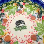 UNIKAT Hedgehog and Pumpkin scalloped bowl, close-up top view of hedgehog figure with acorn and berry border