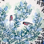 Close-up of bullfinch birds perched among blue florals on Gracious Gonolek stacking bowl