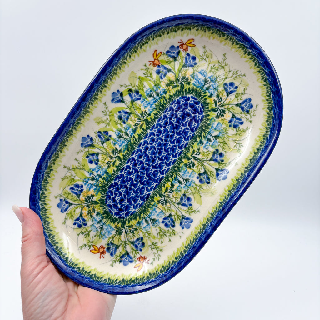 UNIKAT Bluebell Meadow oval platter held in hand, top-down view of full platter