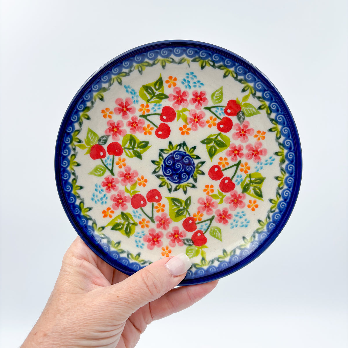 UNIKAT Cherry Blossom plate held in hand, front view showing cherry and pink blossom ring