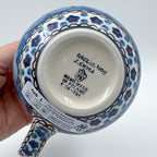 Bottom of Cobalt Poppies bubble mug showing Unikat stamp and artist signature, held in hand