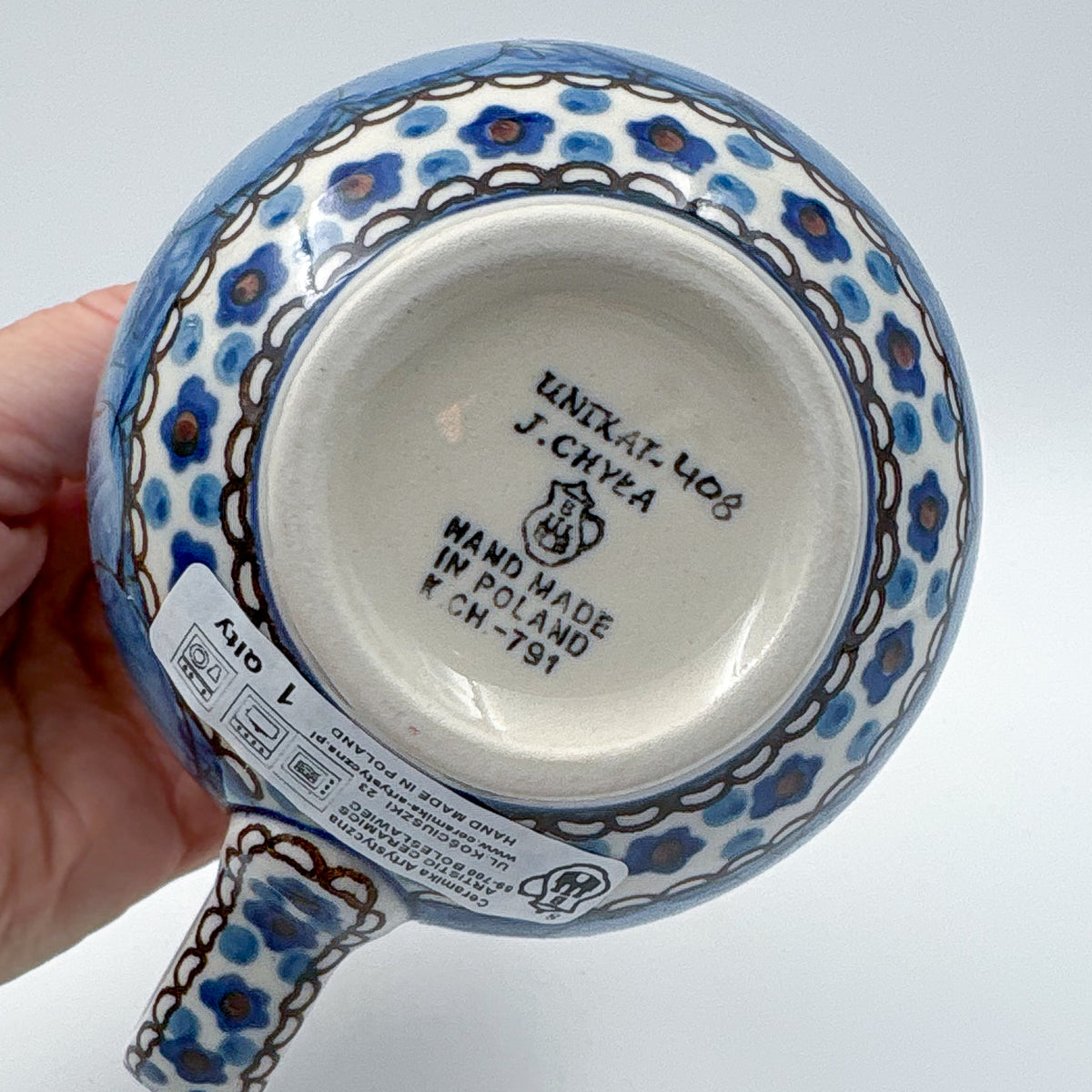 Bottom of Cobalt Poppies bubble mug showing Unikat stamp and artist signature, held in hand