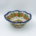 Christmas Cardinals wavy bowl, front view showing poinsettia, pinecone, and cardinal wreath pattern