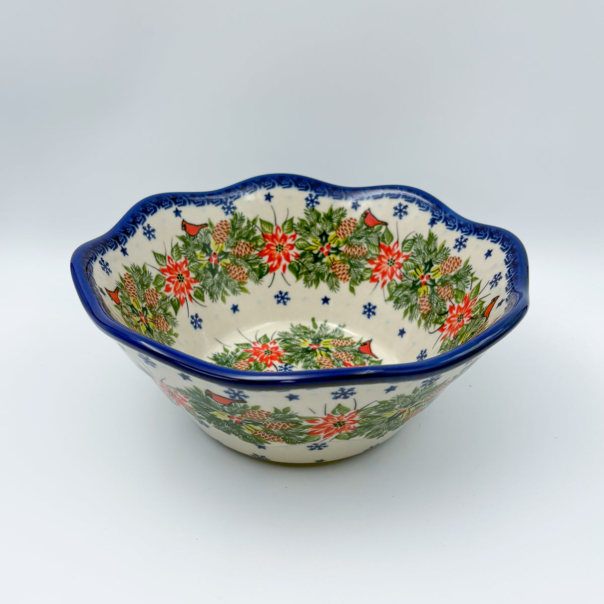 Christmas Cardinals wavy bowl, front view showing poinsettia, pinecone, and cardinal wreath pattern
